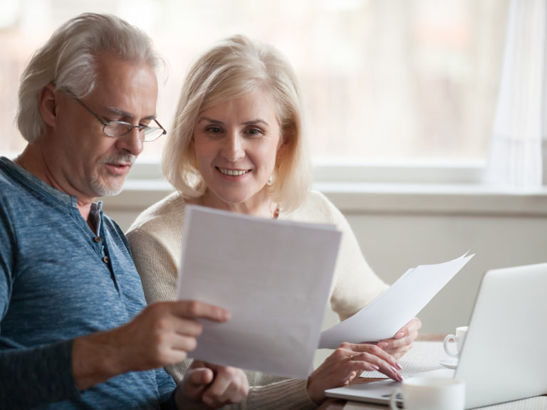 Happy older aged couple holding reading good news in document