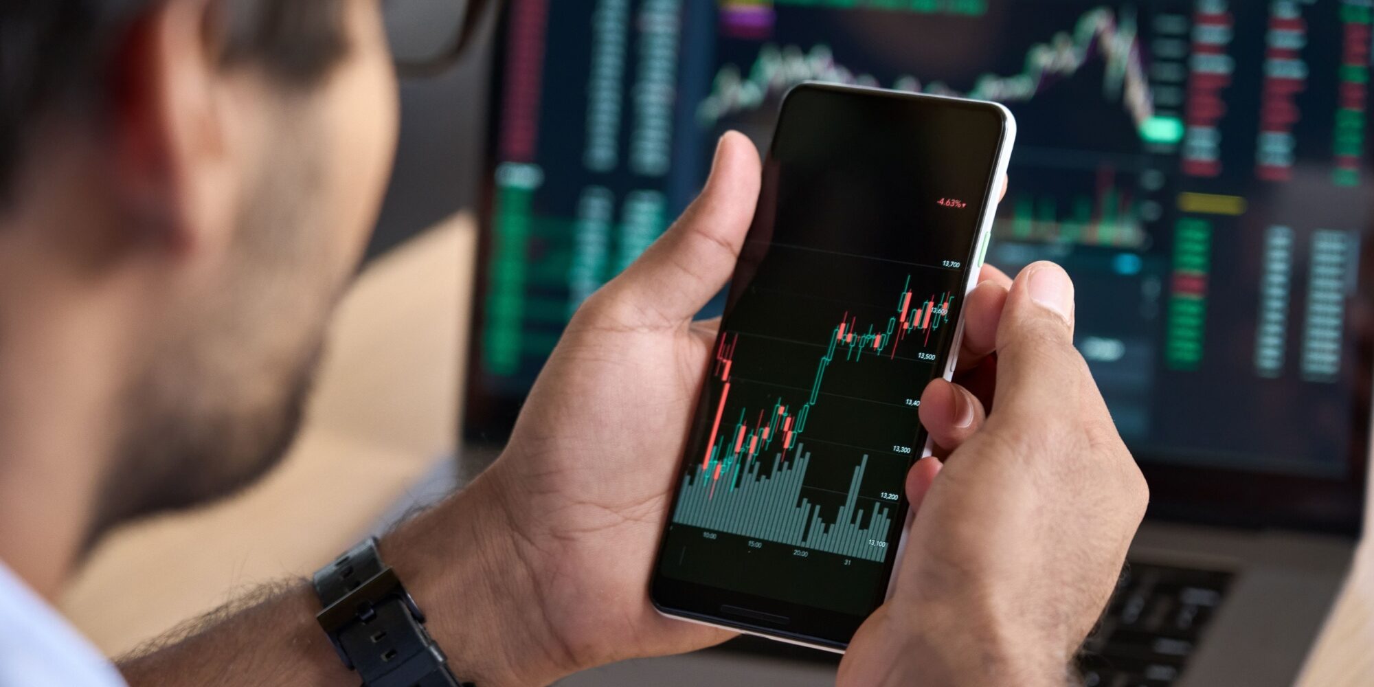 A man looking at a graph showing stock market performance on his phone.