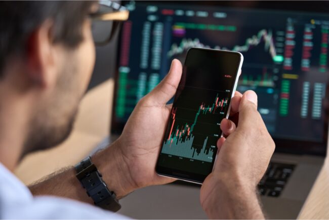 A man looking at a graph showing stock market performance on his phone.
