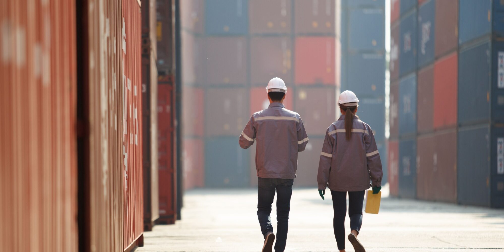 Two workers walking between shopping containers.