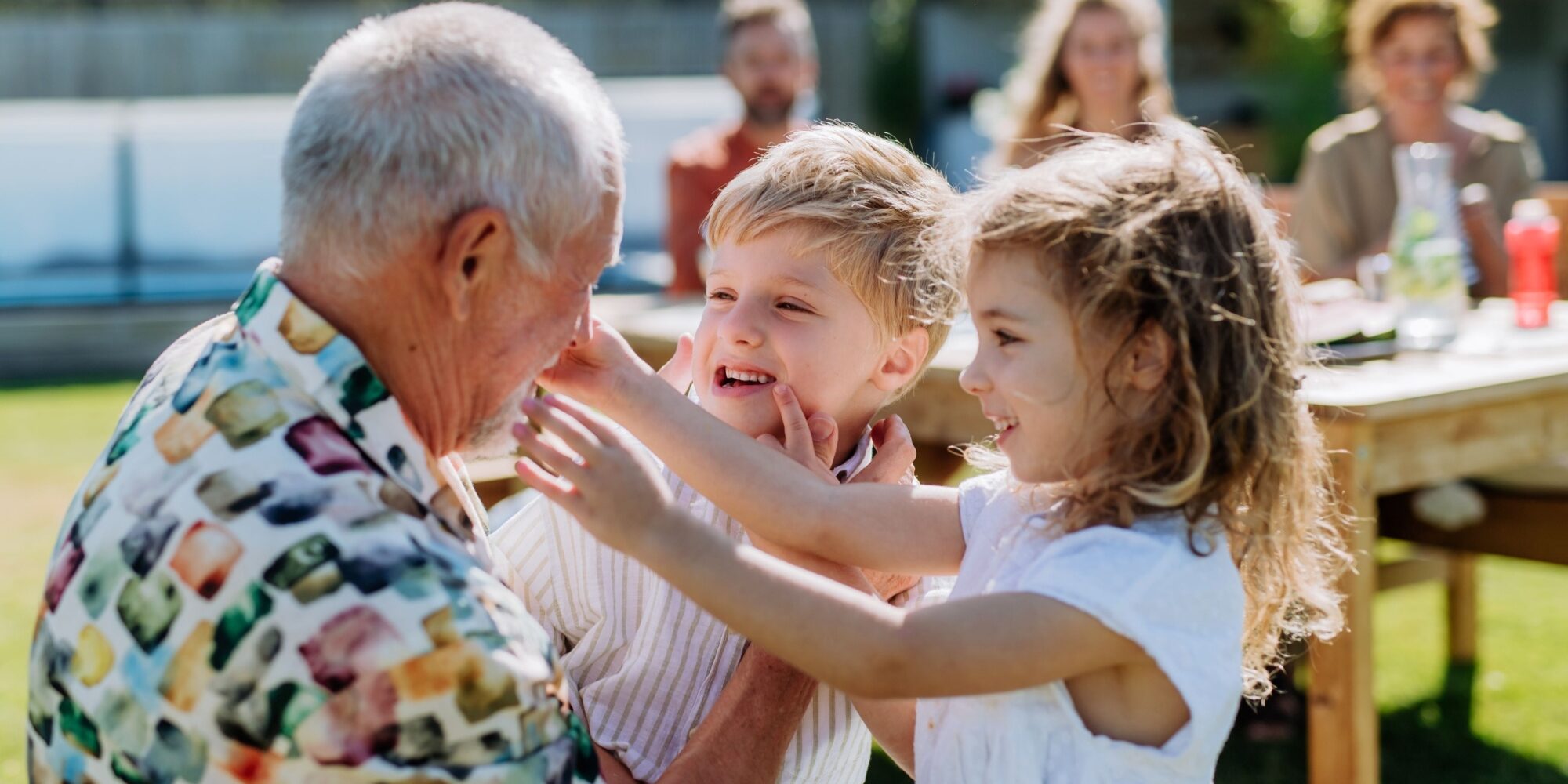 A grandfather playing with his grandchildren outdoors.