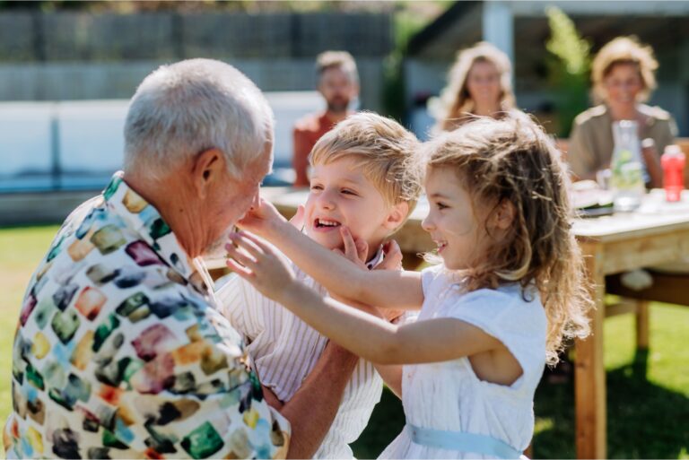 A grandfather playing with his grandchildren outdoors.