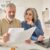A senior couple sit at a laptop comparing multiple documents