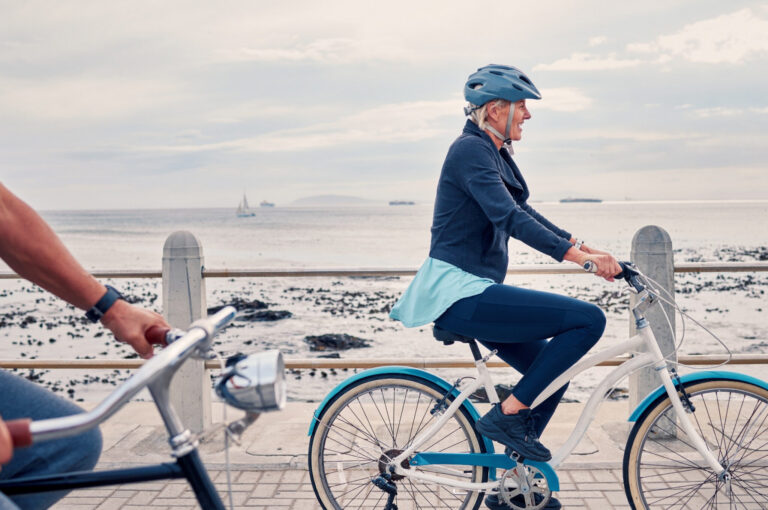 A woman cycling along a beachfront.